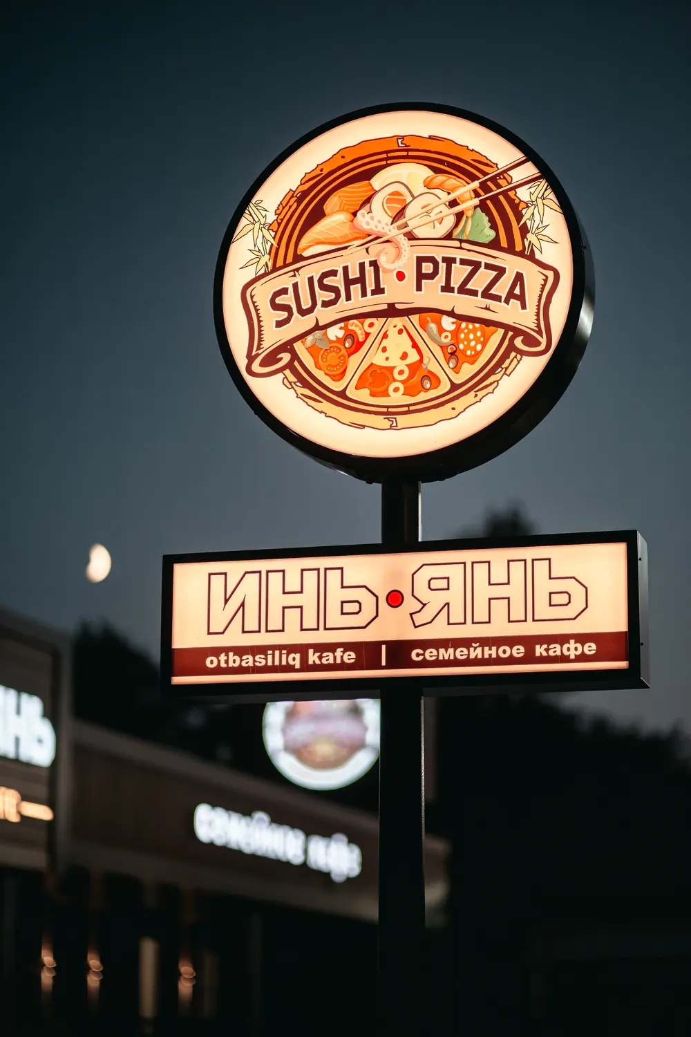 Светящаяся стела кафе Инь-Янь с эмблемой Sushi Pizza вечером